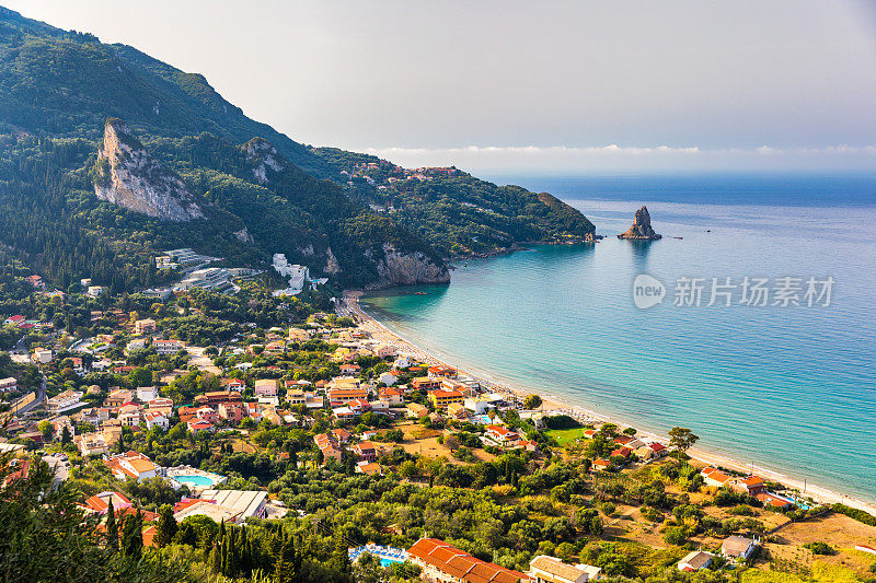 希腊科孚岛的Agios Gordios海滩。希腊科孚岛的Agios Gordios海滩。Agios Gordios海滩的全景，沙滩上有沙滩伞和躺椅。